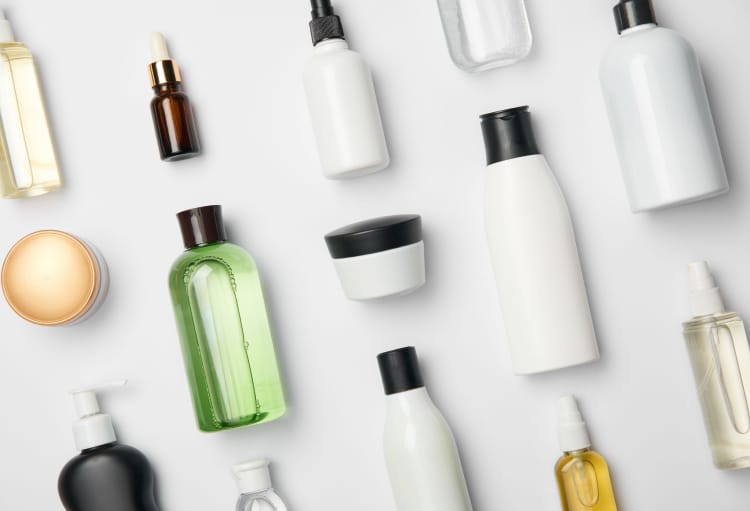 На белой поверхности лежат различные тюбики и баночки для косметики без этикеток.